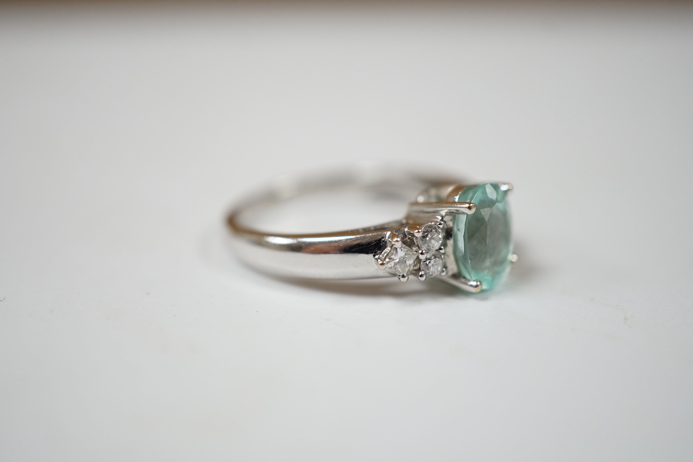 A modern 18ct gold and oval cut paraiba tourmaline set dress ring with six stone diamond set shoulders, size O, gross weight 4.9 grams.
